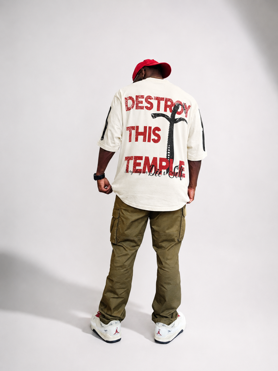 Destroy This Temple® "The Motto" modeled, paired with olive cargo pant, and cream low-top sneakers.